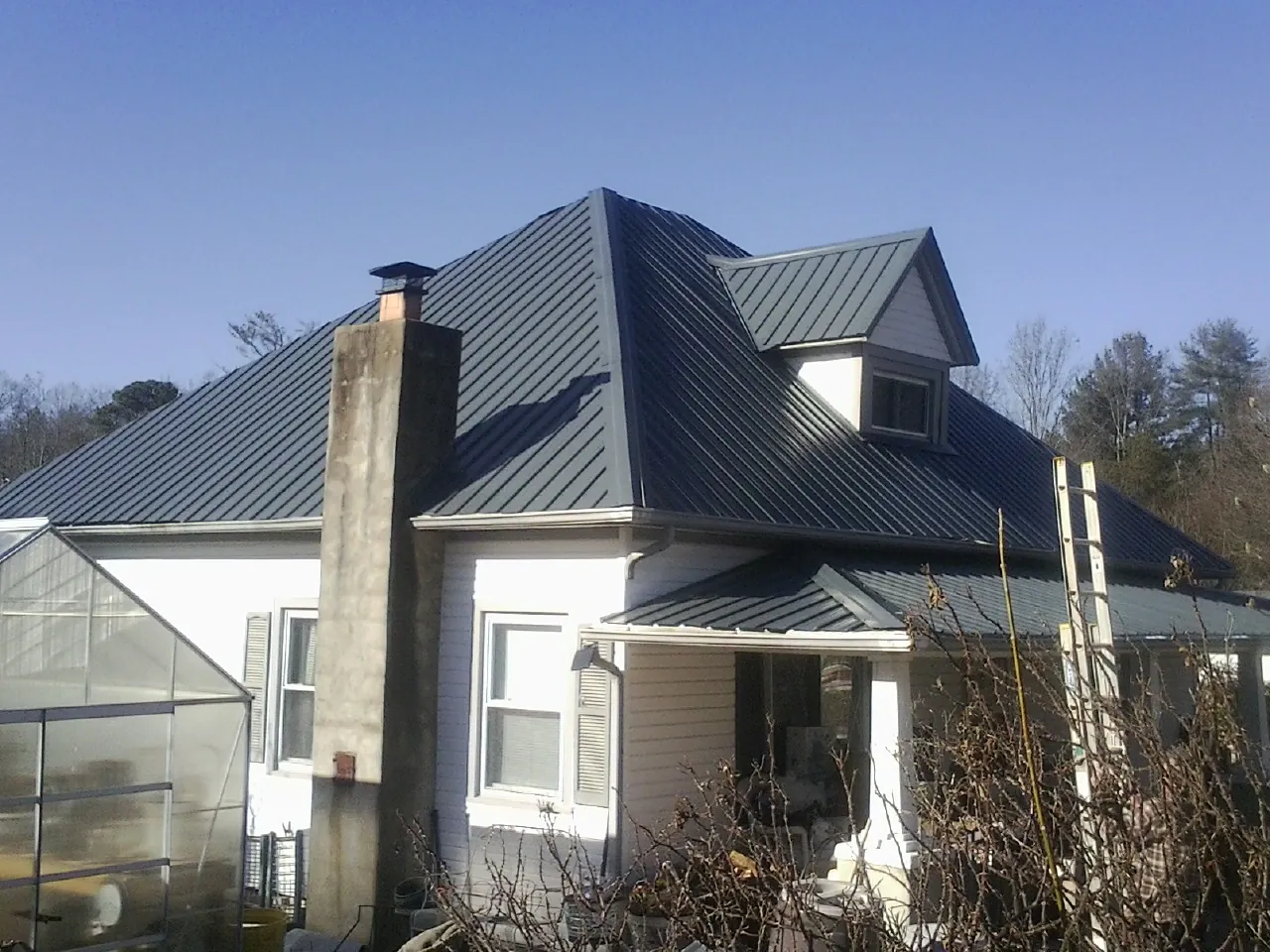 Dark blue standing seam metal roof on a white farmhouse with dormer — Slate & Tile Roof Repair by Roofing Brothers in Brownsburg