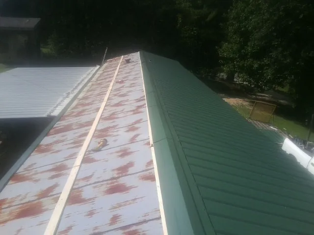 Old rusted panels beside newly installed green metal roofing — Wind Damage Roof Repair by Roofing Brothers in Brownsburg