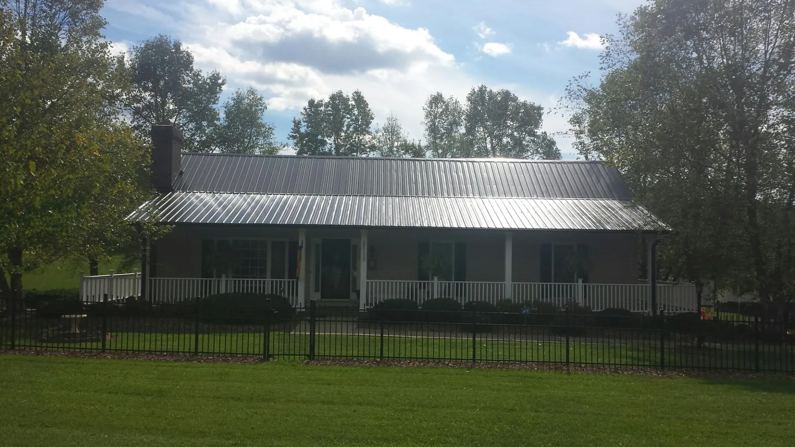 Gray metal roof on a brick ranch with a full width front porch — Gutter Guard Installation work by our crew in Brownsburg