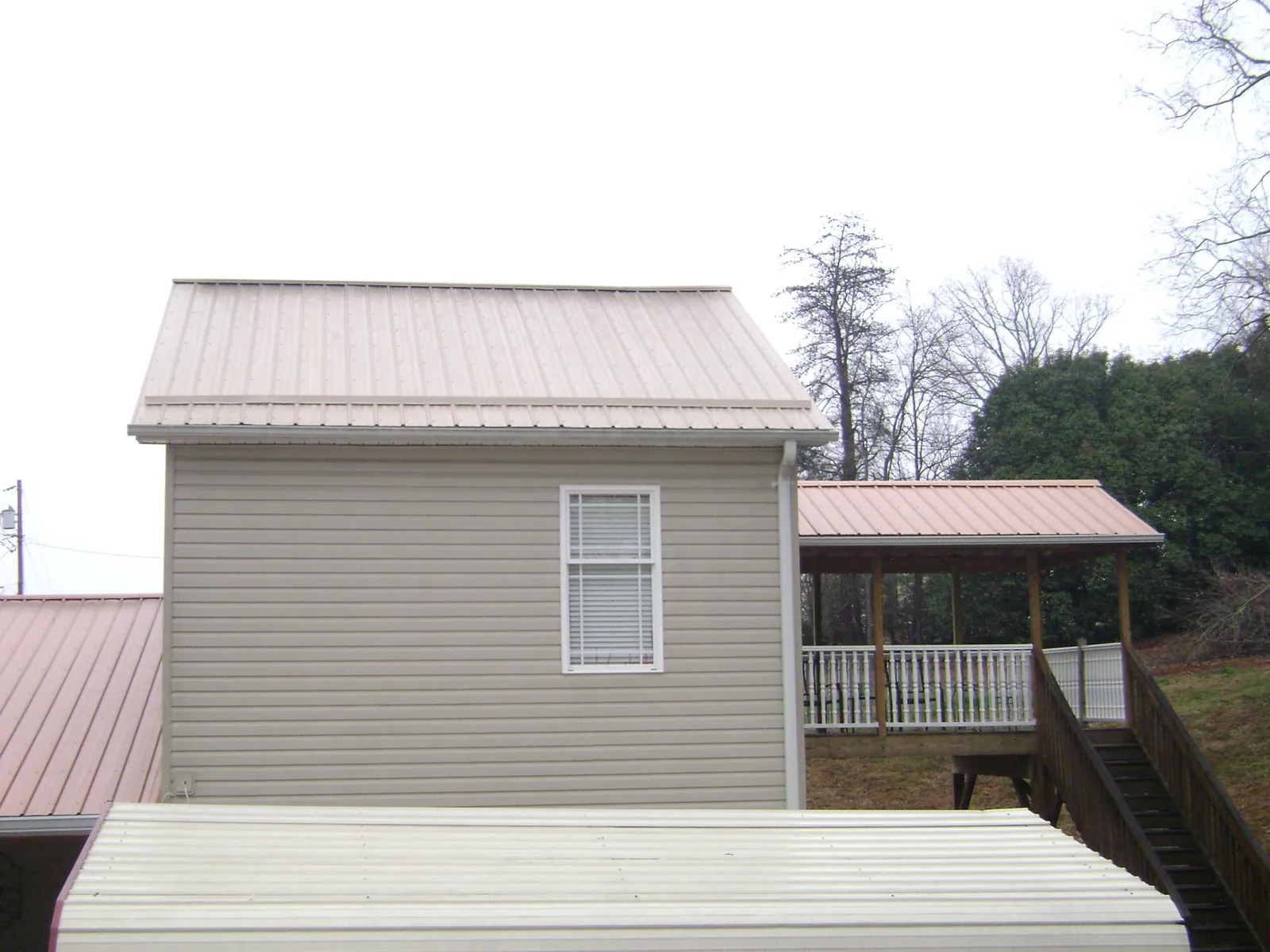 Tan metal roofs on a two story addition and attached porch, from a Roof Replacement job in Brownsburg